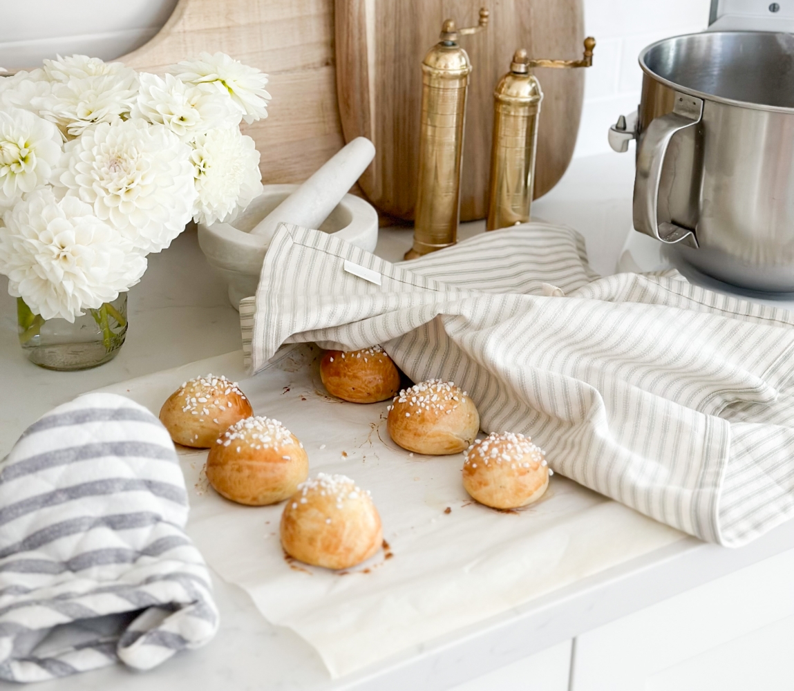 Close-up image of a freshly baked pulla, a traditional Finnish sweet bread, placed next to a steaming cup of coffee and a glass of cold milk. The pulla is beautifully golden-brown and adorned with a hint of powdered sugar. A warm and inviting scene, perfect for settling the delightful debate of whether to enjoy pulla with coffee or milk